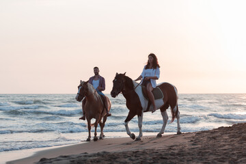Fototapeta na wymiar a loving young couple in summer clothes riding a horse on a sandy beach at sunset. Sea and sunset in the background. Selective focus 