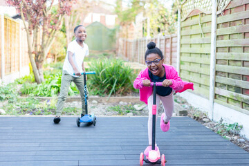 Siblings on push scooters in backyard © Cultura Creative