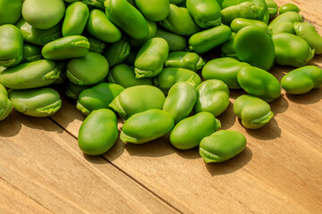 Healthy organic green raw broad beans on a wooden board