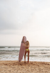 Kobieta z deską surfingową, surferka na tle oceanu na plaży. - obrazy, fototapety, plakaty