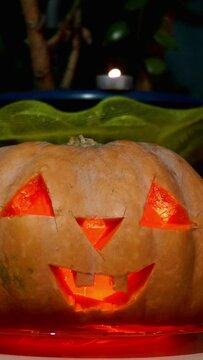 Home decoration with spooky glows halloween pumpkin head Jack Lantern face and burning candle.