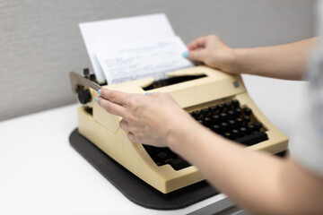 woman typing on a typewriter presses the carriage return lever - obrazy, fototapety, plakaty