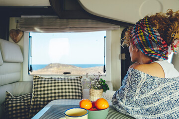 Back view of a woman looking outside the window inside a camper van. Van life and off grid...