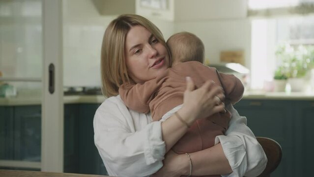 Young adult caucasian mother hugging her baby son at home