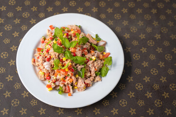 Spicy Tuna Salad with Chili, shallots, corn, mint leaves, carrot, lime and tomatoes cuisine in plate delicious favorite Thai food on table.