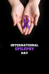 International Epilepsy Day. Woman hands holding purple ribbon on black background. Alzheimer's...