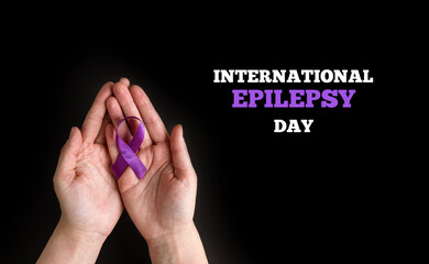 International Epilepsy Day. Woman hands holding purple ribbon on black background. Alzheimer's...