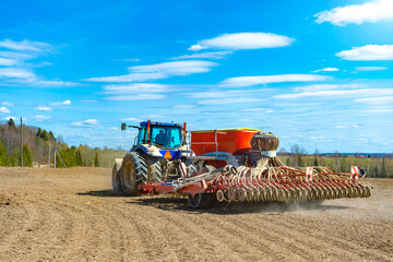 Obraz premium A tractor with a seeder in the field sows grains of wheat or oats to grow grain products.Rear view...