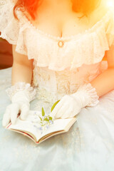 Fototapeta na wymiar Cleavage of a woman in a beautiful blue dress, she is holding a book open and a flower. High quality photo