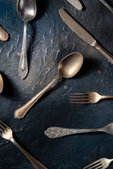 Cutlery flat lay. Spoons, forks, and knives, various table utensils, shot from above on a black background