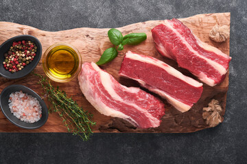 Steak beef. Raw steak New York with rosemary and spices on a piece of parchment paper on old dark stone background. Top view. Mock up.