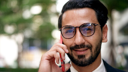 Young businessman with beard wearing eyeglasses talking on mobile phone