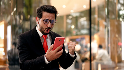 Young Businessman happy with Good News on Mobile phone