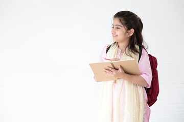 cute Indian girl smiling and writing on notebook for learning, education concept