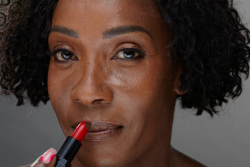 Obraz premium Studio portrait of mature woman using lipstick