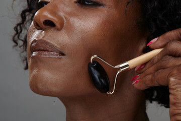 Studio shot of mature woman using face massager