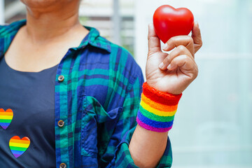 Asian woman holding red hert with rainbow flag, LGBT symbol rights and gender equality, LGBT Pride Month in June, LGBTQ, LGBTI, LGBTQA, LGBTQIA