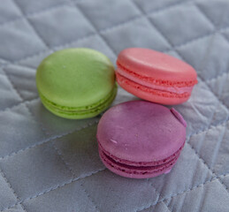 Macarons three cookies on a cloth napkin background. Multicolored french pasta for breakfast.
