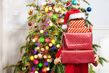 Holding big stack of New Year presents covered with Santa hat