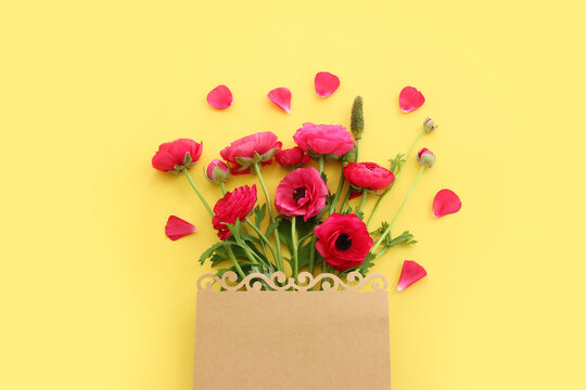 Top view image of pink flowers composition and empty note over yellow pastel background