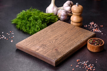 A wooden cutting board with spices, herbs, cherry tomatoes and salt on a black concrete background - Powered by Adobe