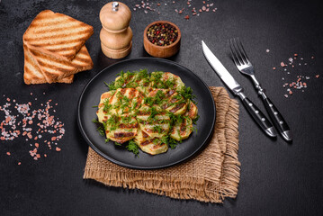 Fototapeta na wymiar Delicious grilled potato slices with spices and herbs on a black plate