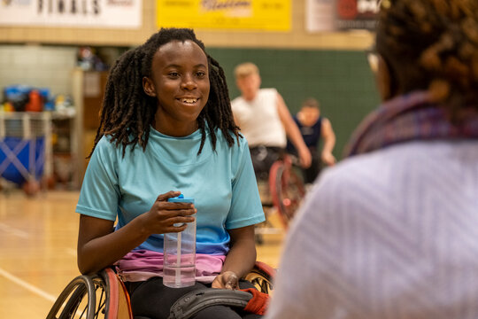 Teenage girl in wheelchair having water break during basketball game