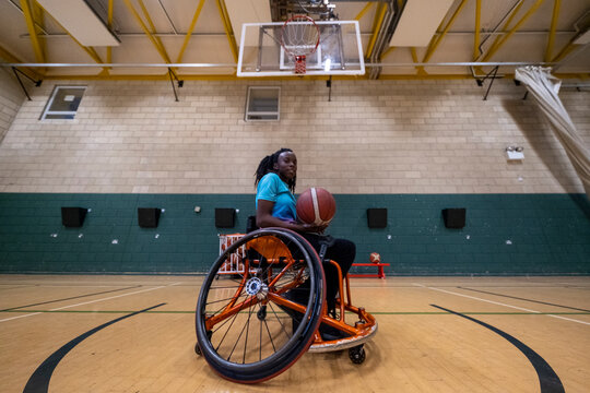 Teenage girl in wheelchair practicing basketball