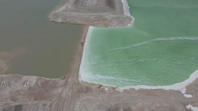 bird's eye view of a dike in the dead sea with the clear color differences of the water on both shores in jordan