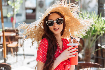 Summer season. Smiling girl in sunglasses, straw hat and red polka-dot dress