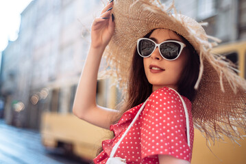 Summer girl with straw hat and sunglasses walk on old city street
