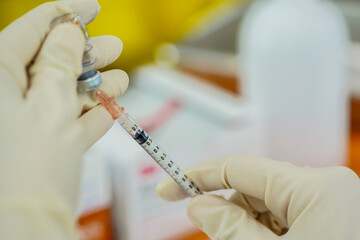 Medical team in full uniform holding syringe taking covid 19 corona virus vaccine from vial bottle...