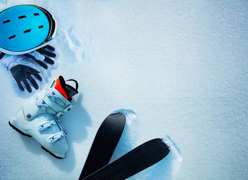 White alpine ski boot helmet and gloves in snow from above