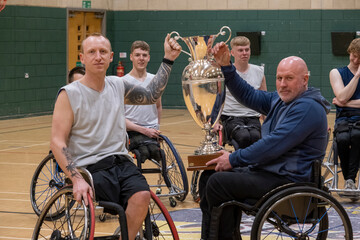 Team of basketball players in wheelchairs with trophy