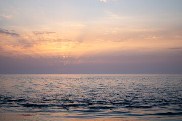 Obraz premium Sunset over the sea. Sunbeams through the clouds.