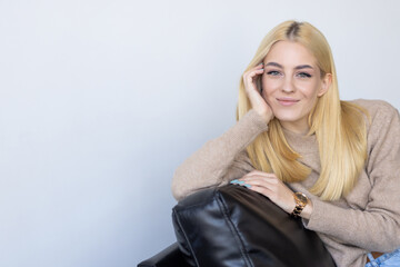 Smiling pretty blonde young woman relaxing on a couch at home