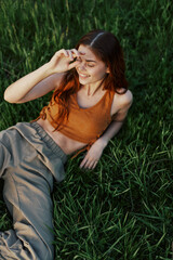 The view from above is a woman lying on the green grass in the park and relaxing in nature smiling and enjoying life. The concept of a healthy lifestyle