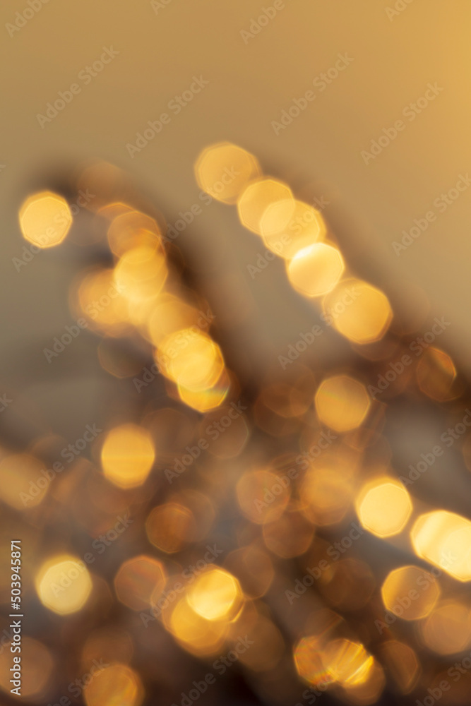 Poster defocused image of lights, golden hue. layered golden bokeh spots. high resolution abstract backgrou