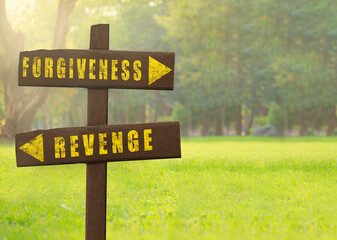 Wooden signs Forgiveness versus Revenge on a natural green background copy space.