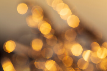 Defocused image of lights, golden hue. Layered golden bokeh spots. High resolution abstract background with copy space.