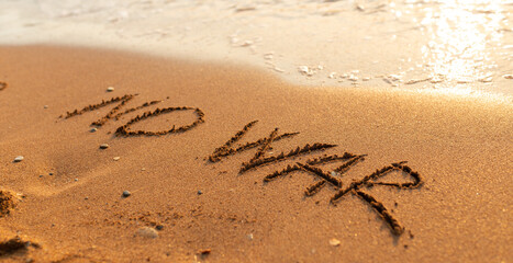 Words written in the sand on the beach. The words No War and written in the Sand with the Ocean in the background. Protest War sign written in sand. World Peace. No War