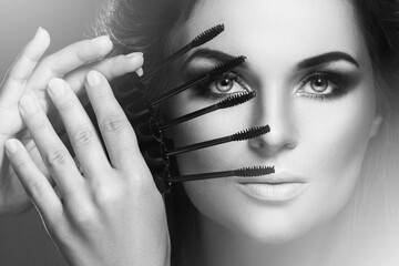 Stunning woman with beautiful make-up holding  lot of  mascara wands near her face
