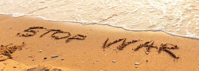 Words written in the sand on the beach. The words Stop War and written in the Sand with the Ocean in the background. Protest War sign written in sand. World Peace. No War
