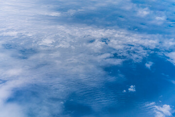 飛行機の窓から眺める空の景色　青空と流れる白い雲