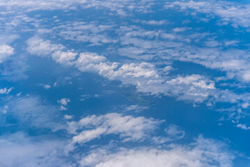 飛行機の窓から眺める空の景色　青空と流れる白い雲