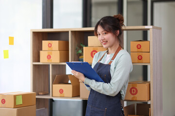 Freelance SME Startup small business entrepreneur, Attractive Asian young woman using a laptop with a box doing a sales accounts report online marketing packaging and delivery SME concept.