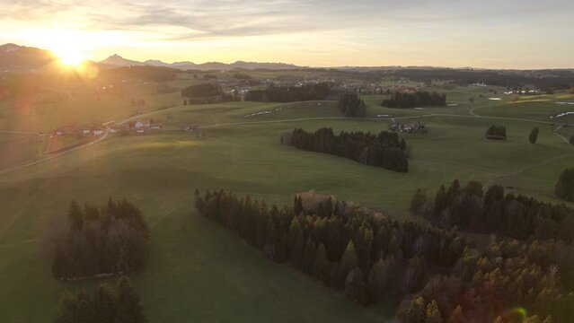 Allgaeu landscape with mountains, fields and forests in sunset contre-jour drone time lapse