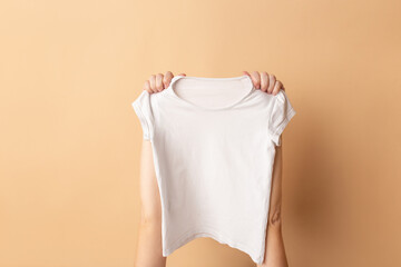 Female hands holding a white t-shirt close-up. Mock-up