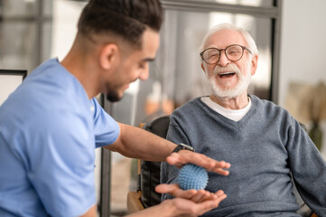 Patient having his hand massaged with a spiky massage ball - 503947205