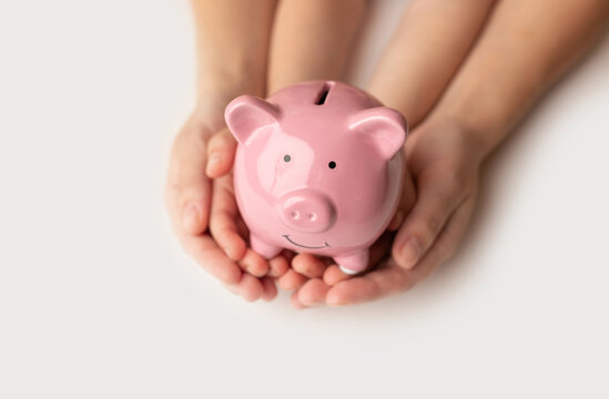A woman and child holding a piggy bank in the shape of a pink pig, she is organizing money to divide it into savings and buy funds to make it grow. Personal finance concept